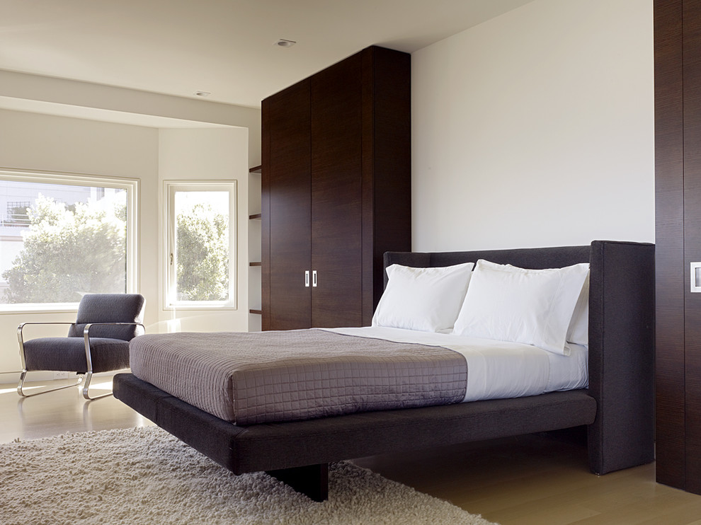 Photo of a modern bedroom in San Francisco with white walls and light hardwood floors.