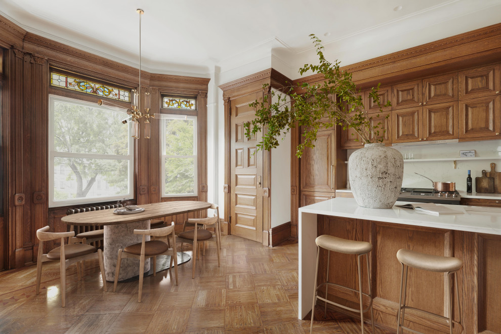 Immagine di una grande sala da pranzo aperta verso la cucina minimalista con pareti bianche, pavimento in legno massello medio, nessun camino, pavimento marrone e pannellatura