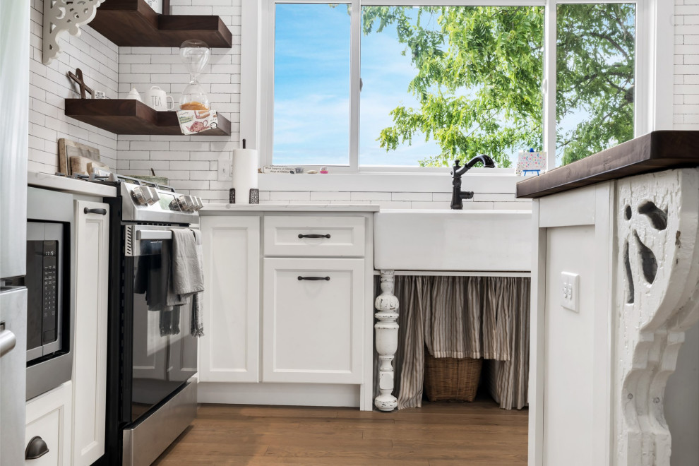 Inspiration for a mid-sized country eat-in kitchen in Cincinnati with a double-bowl sink, recessed-panel cabinets, white cabinets, wood benchtops, white splashback, subway tile splashback, stainless steel appliances, medium hardwood floors, with island, beige floor and white benchtop.