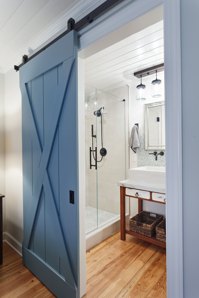 Design ideas for a country 3/4 bathroom in Charlotte with brown cabinets, an alcove shower, white walls, medium hardwood floors, a vessel sink, brown floor, a hinged shower door, glass tile, marble benchtops, white benchtops and flat-panel cabinets.