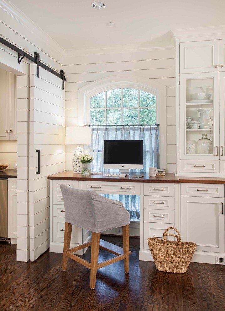 Traditional home office in Charlotte with white walls, dark hardwood floors and a built-in desk.