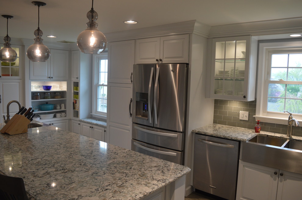 Enclosed kitchen - large transitional u-shaped ceramic tile and gray floor enclosed kitchen idea with a farmhouse sink, raised-panel cabinets, white cabinets, quartz countertops, gray backsplash, glass tile backsplash, stainless steel appliances and an island
