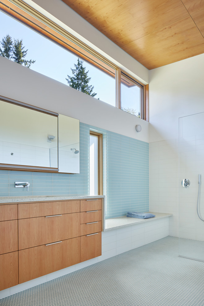 Design ideas for a contemporary bathroom in Seattle with flat-panel cabinets, medium wood cabinets, a curbless shower, a one-piece toilet, blue tile, glass tile, white walls, mosaic tile floors, a trough sink, recycled glass benchtops, blue floor, an open shower and multi-coloured benchtops.