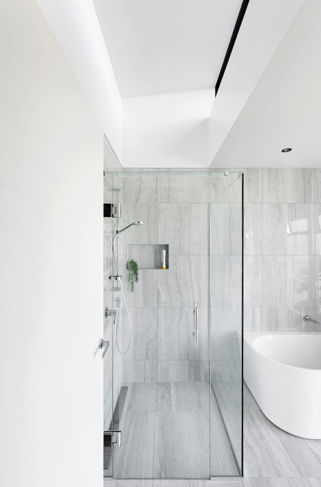 На фото: большая главная ванная комната в современном стиле с белыми фасадами, отдельно стоящей ванной, угловым душем, унитазом-моноблоком, серой плиткой, мраморной плиткой, белыми стенами, полом из керамической плитки, монолитной раковиной, столешницей терраццо, серым полом, душем с распашными дверями, белой столешницей, тумбой под две раковины и подвесной тумбой