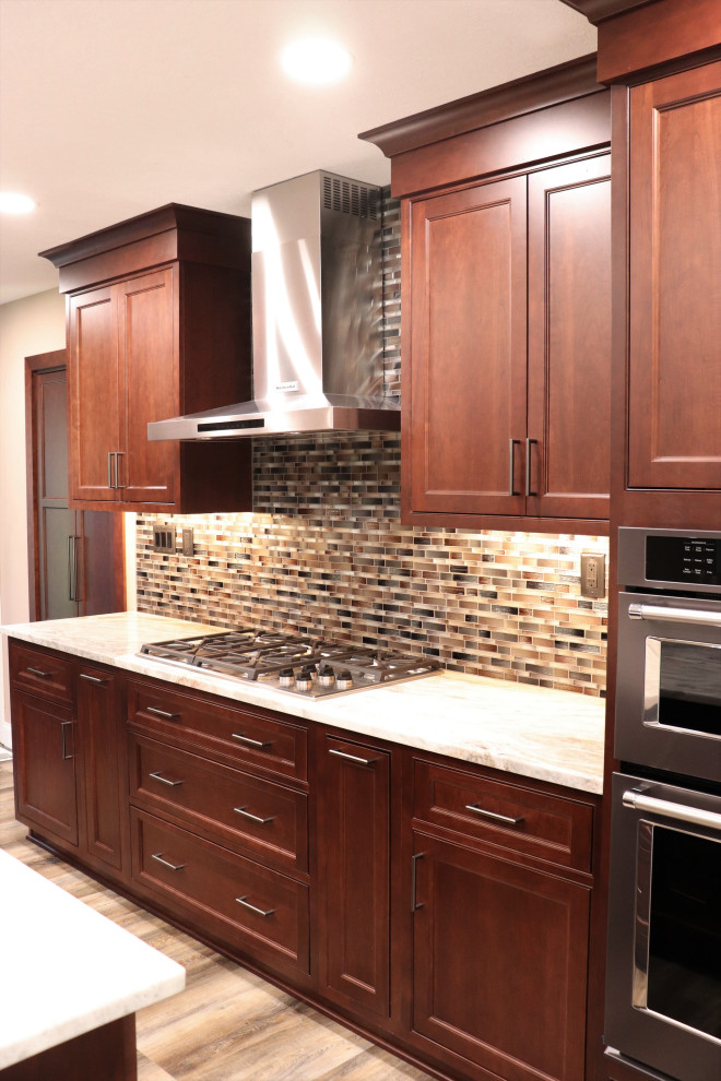 Inspiration for a large transitional l-shaped enclosed kitchen remodel with an undermount sink, beaded inset cabinets, granite countertops, multicolored backsplash, an island and beige countertops