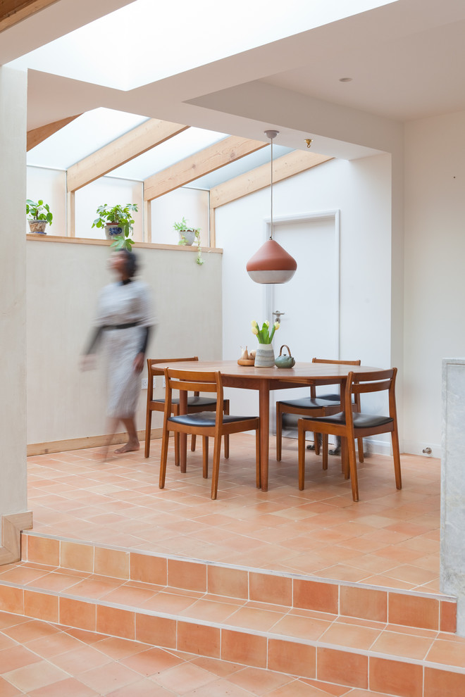 Mid-sized dining room in London with terra-cotta floors, white walls, no fireplace and orange floor.
