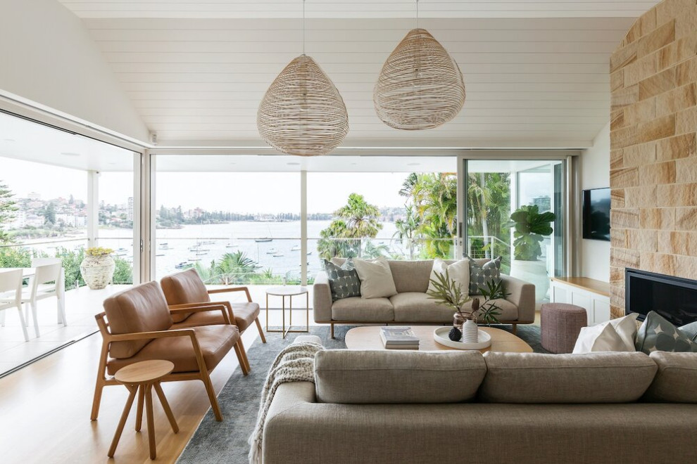 Large beach style open concept family room in Sydney with white walls, medium hardwood floors, a wall-mounted tv, timber and a ribbon fireplace.