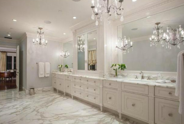 This is an example of an expansive traditional bathroom in Los Angeles with an undermount sink, furniture-like cabinets, white cabinets, marble benchtops, a corner tub, an alcove shower, a one-piece toilet, white tile, stone slab, white walls and marble floors.