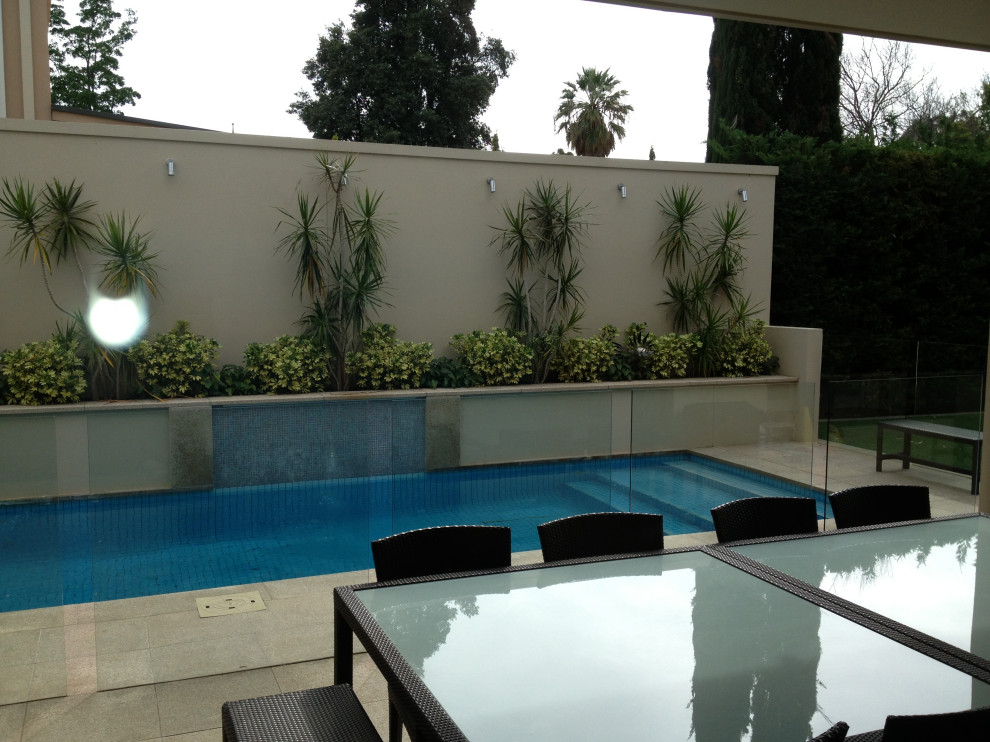 Ispirazione per una grande piscina monocorsia minimal rettangolare dietro casa con una dépendance a bordo piscina e pavimentazioni in pietra naturale