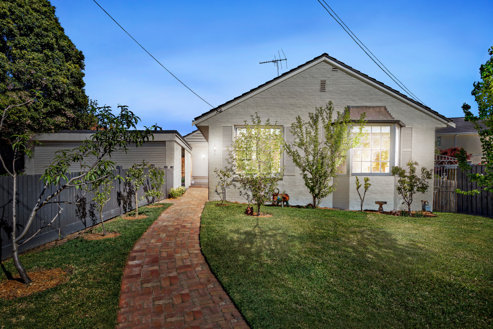 This is an example of a large transitional one-storey brick grey house exterior in Melbourne with a tile roof.