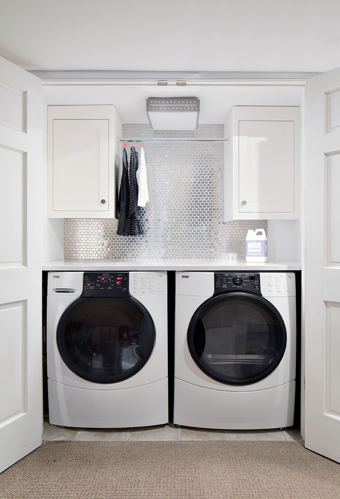 Photo of a transitional single-wall laundry cupboard in New York with white cabinets, white walls, a side-by-side washer and dryer and white benchtop.