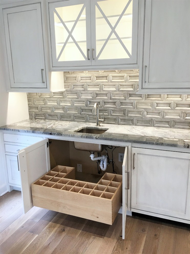 Inspiration for a mid-sized transitional single-wall wet bar in Other with an undermount sink, beaded inset cabinets, grey cabinets, marble benchtops, grey splashback, medium hardwood floors and brown floor.