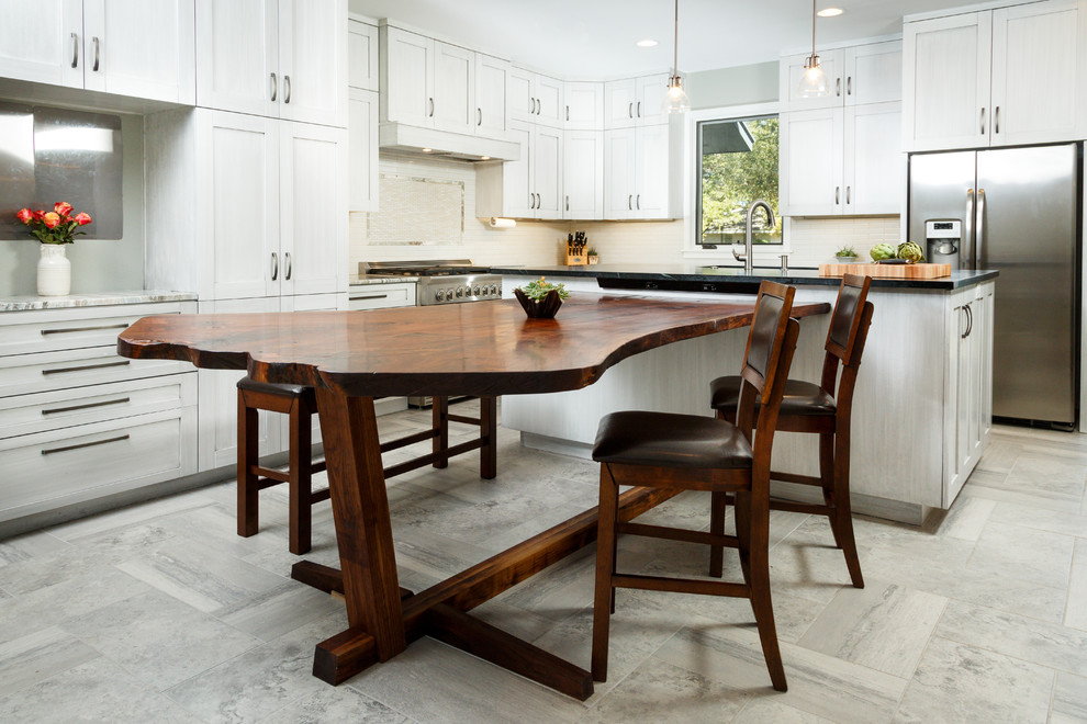 Large transitional l-shaped porcelain tile eat-in kitchen photo in Austin with a single-bowl sink, shaker cabinets, gray cabinets, soapstone countertops, white backsplash, ceramic backsplash, stainless steel appliances and an island