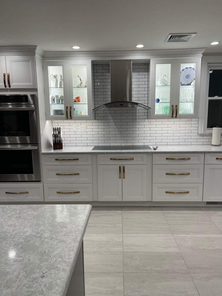 Photo of a large modern l-shaped kitchen pantry in New York with a single-bowl sink, recessed-panel cabinets, white cabinets, quartzite benchtops, white splashback, porcelain splashback, stainless steel appliances, vinyl floors, no island, grey floor, grey benchtop and vaulted.