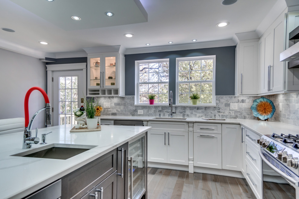 This is an example of a large modern l-shaped eat-in kitchen in DC Metro with a drop-in sink, shaker cabinets, white cabinets, marble benchtops, grey splashback, mosaic tile splashback, stainless steel appliances, plywood floors, with island, grey floor and white benchtop.