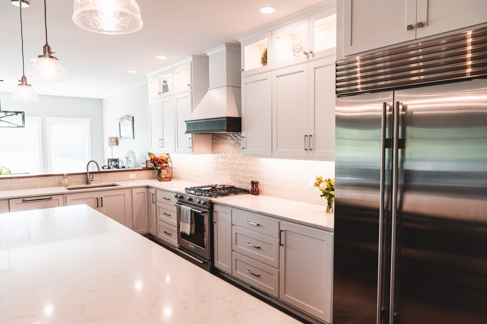 Kitchen pantry - large transitional l-shaped vinyl floor and brown floor kitchen pantry idea with an undermount sink, shaker cabinets, white cabinets, quartz countertops, gray backsplash, subway tile backsplash, stainless steel appliances, an island and white countertops