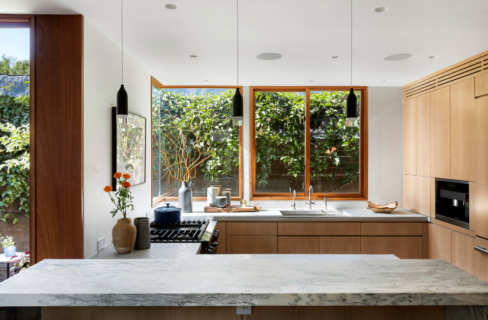 Inspiration for a small contemporary u-shaped enclosed kitchen in Los Angeles with a submerged sink, granite worktops, window splashback, black appliances, a breakfast bar, flat-panel cabinets, medium wood cabinets and grey worktops.