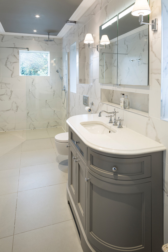 This is an example of a large transitional kids wet room bathroom in Dublin with a wall-mount toilet, white tile, porcelain tile, white walls, porcelain floors, an undermount sink, quartzite benchtops and grey floor.