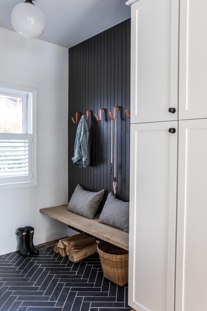 Photo of a transitional entryway in Boston with white walls, black floor and panelled walls.