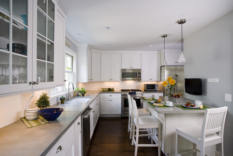Inspiration for a mid-sized traditional l-shaped separate kitchen in Chicago with shaker cabinets, stainless steel appliances, concrete benchtops, a single-bowl sink, white cabinets, white splashback, subway tile splashback, grey benchtop, medium hardwood floors, with island and brown floor.
