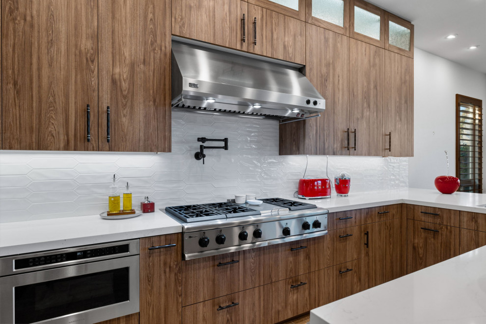 Enclosed kitchen - rustic l-shaped slate floor and beige floor enclosed kitchen idea with a single-bowl sink, flat-panel cabinets, medium tone wood cabinets, quartzite countertops, white backsplash, glass sheet backsplash, stainless steel appliances, a peninsula and white countertops