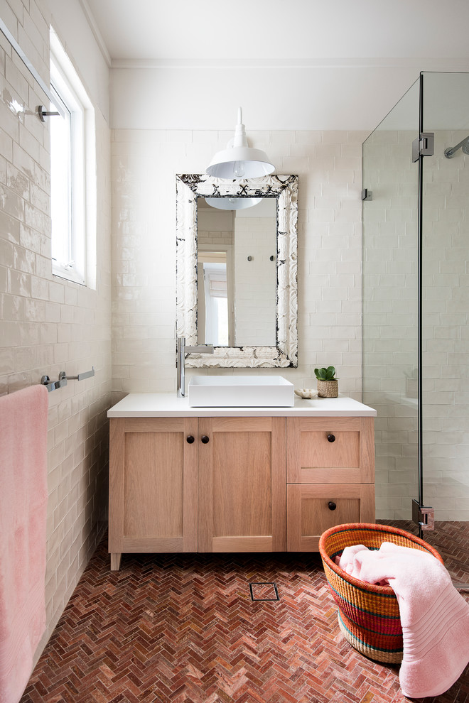 Design ideas for a mid-sized shabby-chic style 3/4 bathroom in Sydney with shaker cabinets, light wood cabinets, beige walls, a vessel sink, a double shower, white tile, porcelain tile, terra-cotta floors, solid surface benchtops, red floor and a hinged shower door.