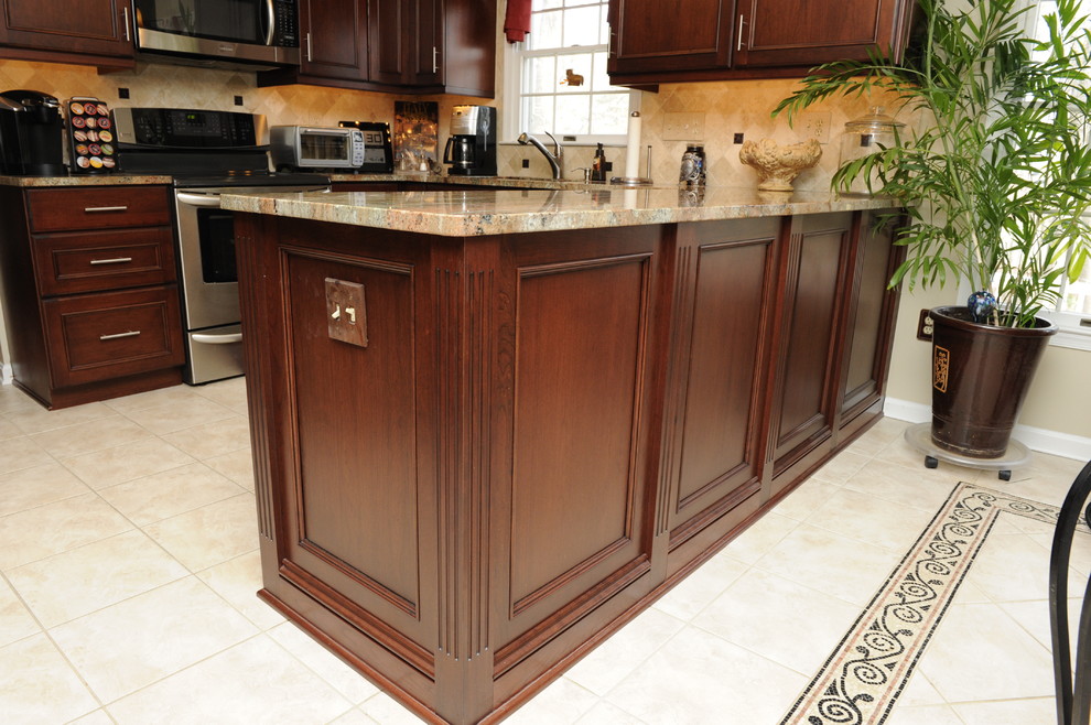 Mid-sized transitional u-shaped limestone floor enclosed kitchen photo in Baltimore with an undermount sink, beaded inset cabinets, dark wood cabinets, granite countertops, beige backsplash, stone tile backsplash, stainless steel appliances and a peninsula