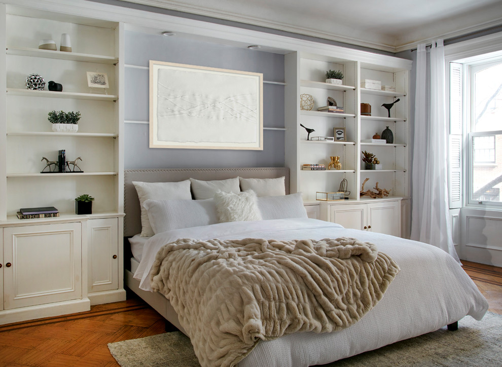 Large transitional bedroom in New York with blue walls, medium hardwood floors and brown floor.