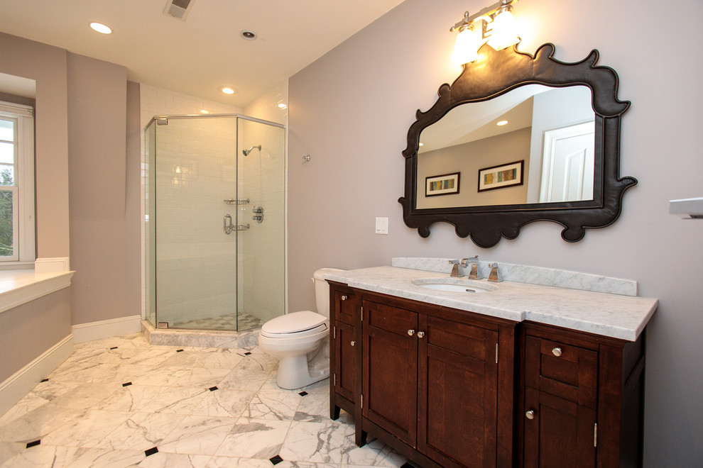 Photo of a mid-sized traditional 3/4 bathroom in Boston with furniture-like cabinets, a corner shower, a two-piece toilet, gray tile, grey walls, ceramic floors, a drop-in sink, solid surface benchtops, white floor and a hinged shower door.