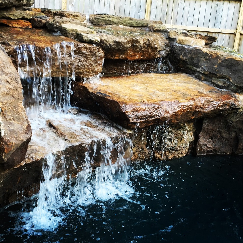 Example of a mid-sized mountain style backyard stone and custom-shaped lap pool fountain design in Houston