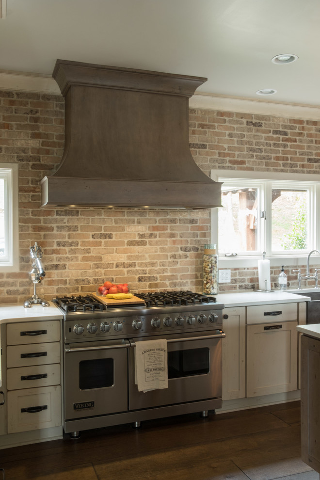 Inspiration for a large transitional galley dark wood floor and brown floor open concept kitchen remodel with a farmhouse sink, shaker cabinets, quartz countertops, brown backsplash, brick backsplash, stainless steel appliances and an island