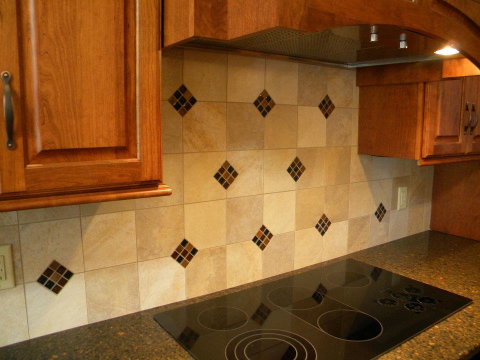 Elegant kitchen photo with raised-panel cabinets, medium tone wood cabinets, granite countertops, beige backsplash, cement tile backsplash and black appliances