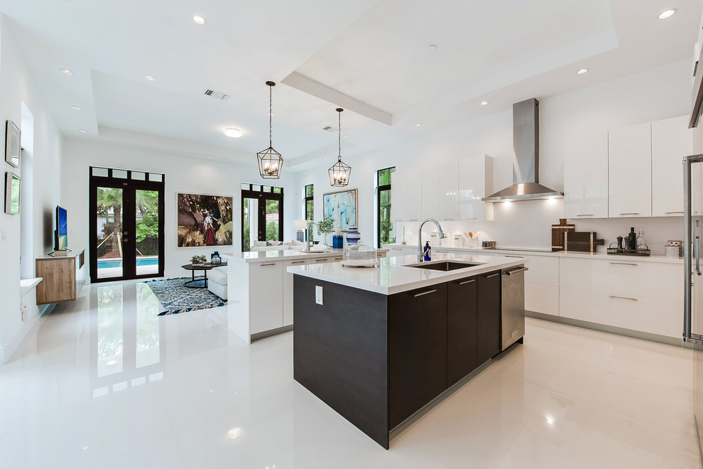 Inspiration for a contemporary u-shaped open plan kitchen in Austin with an undermount sink, flat-panel cabinets, white cabinets, white splashback, stainless steel appliances, with island and white floor.