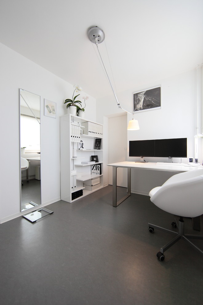 Small modern study room in Berlin with white walls, a freestanding desk, no fireplace and linoleum floors.