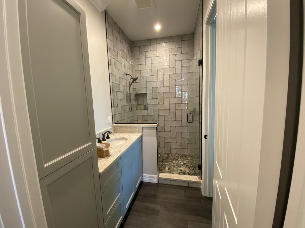 This is an example of a small country master bathroom in Miami with shaker cabinets, grey cabinets, an alcove shower, a two-piece toilet, gray tile, subway tile, white walls, vinyl floors, an undermount sink, engineered quartz benchtops, grey floor, a hinged shower door and multi-coloured benchtops.