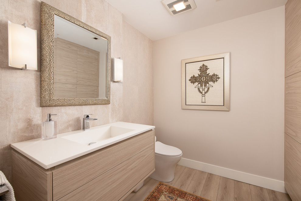 Aménagement d'un WC et toilettes moderne en bois clair avec un placard à porte plane, un bidet, un mur beige, un sol en vinyl, un lavabo intégré, un plan de toilette en quartz, un sol marron, un plan de toilette blanc et meuble-lavabo suspendu.
