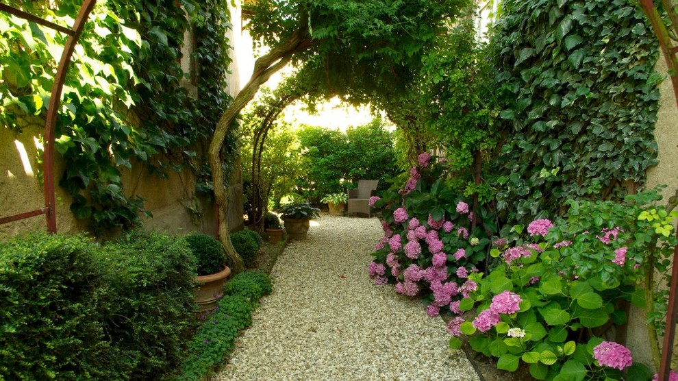 This is an example of a traditional shaded formal garden in Bordeaux with a garden path and gravel.