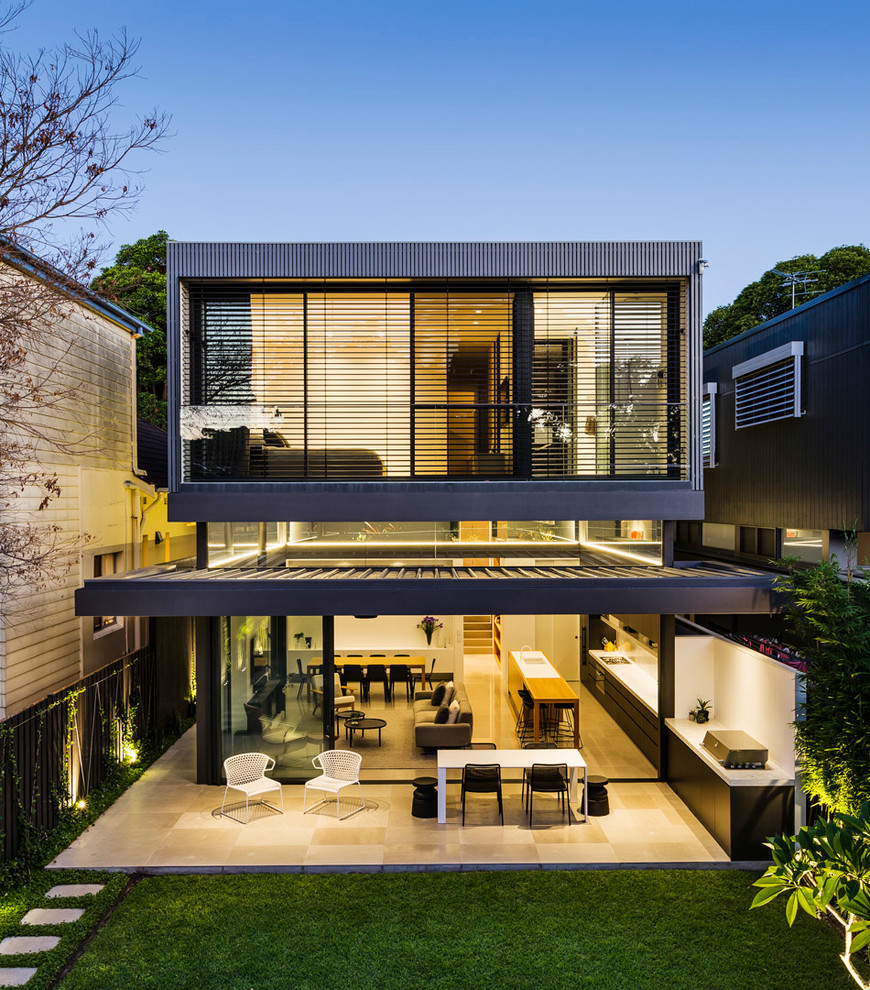 This is an example of a contemporary two-storey house exterior in Sydney with wood siding, a flat roof and a metal roof.