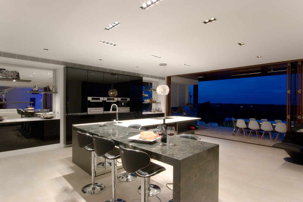This is an example of a modern eat-in kitchen in Brisbane with flat-panel cabinets, black cabinets, granite benchtops, an undermount sink, stainless steel appliances and ceramic floors.