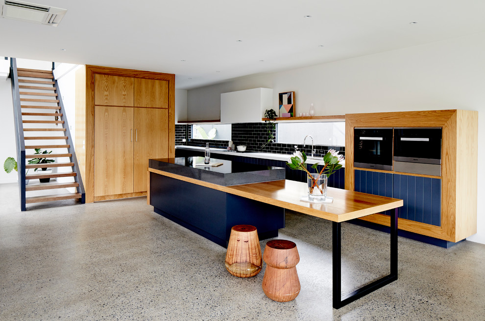 Inspiration for a contemporary galley open plan kitchen in Melbourne with black splashback, subway tile splashback, concrete floors and with island.