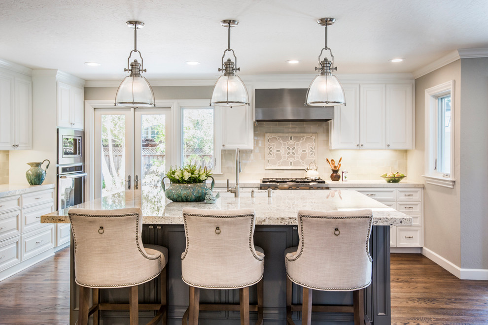 Large transitional l-shaped kitchen in San Francisco with a farmhouse sink, beaded inset cabinets, white cabinets, granite benchtops, white splashback, porcelain splashback, stainless steel appliances, medium hardwood floors and with island.