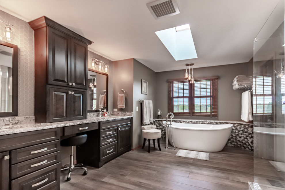 Photo of a large traditional master bathroom in Chicago with raised-panel cabinets, brown cabinets, a freestanding tub, an alcove shower, a one-piece toilet, brown tile, glass tile, beige walls, porcelain floors, an undermount sink, granite benchtops, brown floor, a hinged shower door, brown benchtops, an enclosed toilet, a double vanity and a built-in vanity.