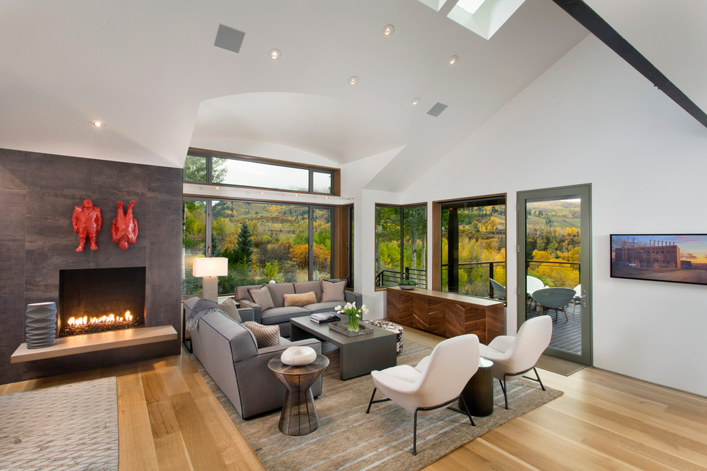 This is an example of a contemporary formal open concept living room in Denver with white walls, light hardwood floors and a standard fireplace.