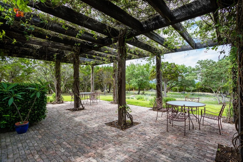Example of a cottage brick patio design in Austin with a pergola