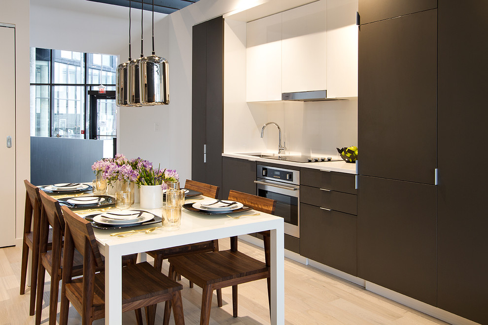 Photo of a small contemporary single-wall eat-in kitchen in Toronto with flat-panel cabinets, grey cabinets, white splashback, stainless steel appliances, light hardwood floors, an undermount sink and white benchtop.