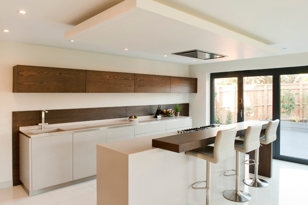 Mid-sized contemporary u-shaped eat-in kitchen in Essex with an undermount sink, flat-panel cabinets, white cabinets, solid surface benchtops, porcelain floors and with island.