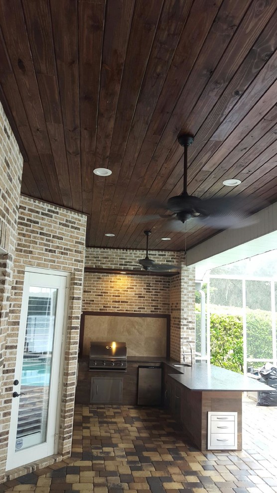 This is an example of a mid-sized transitional backyard patio in Tampa with a roof extension.
