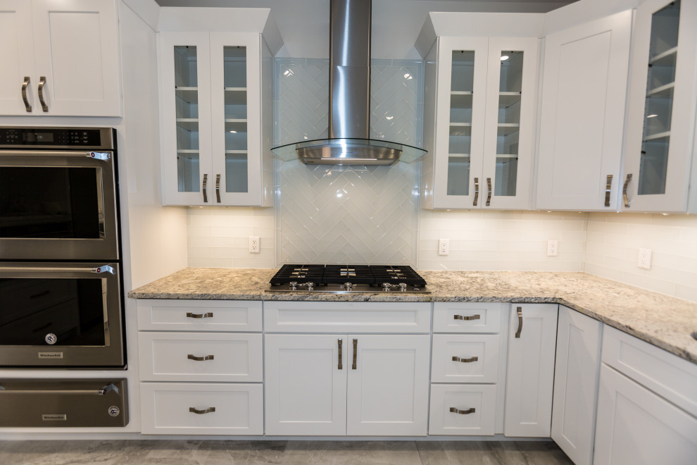 Inspiration for a large transitional u-shaped open plan kitchen in St Louis with an undermount sink, shaker cabinets, white cabinets, granite benchtops, white splashback, glass tile splashback, stainless steel appliances, ceramic floors, with island, grey floor and beige benchtop.