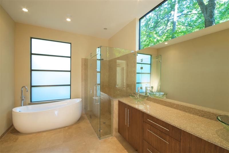 Large modern master bathroom in Dallas with flat-panel cabinets, medium wood cabinets, a freestanding tub, a corner shower, beige walls, marble floors, a vessel sink, brown floor and a hinged shower door.