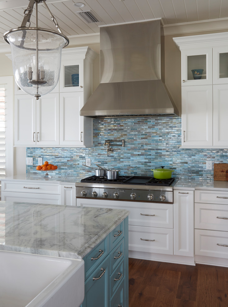 Large beach style l-shaped open plan kitchen in Jacksonville with a farmhouse sink, recessed-panel cabinets, turquoise cabinets, quartzite benchtops, blue splashback, glass tile splashback, stainless steel appliances, medium hardwood floors, with island and brown floor.